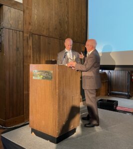 the eagle award is being presented to Alex Levy by Ken Hellendall on the stage of EDITS.